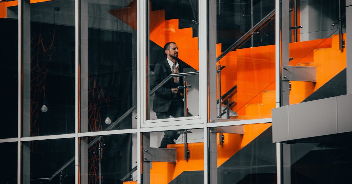 A businessman in a suit walking on a striking orange staircase in a modern office building.